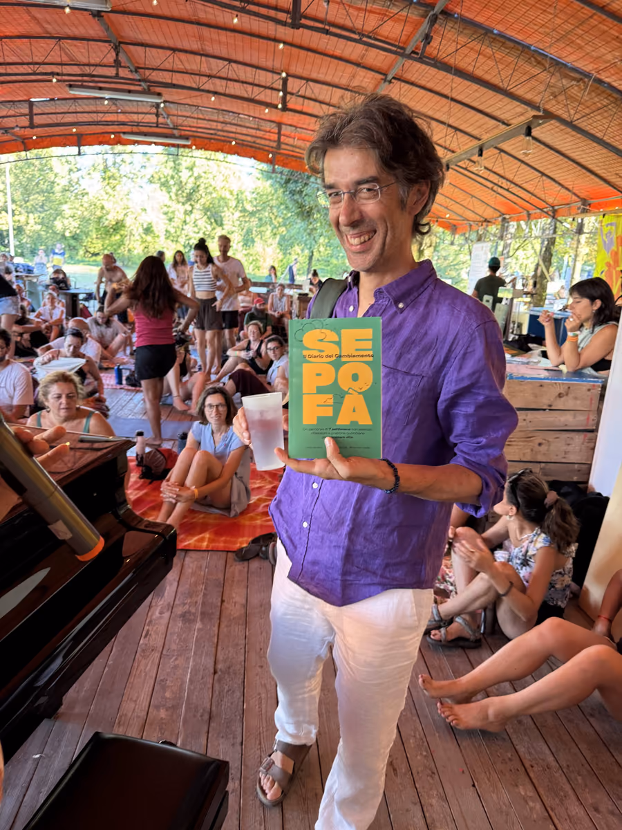 Un uomo con la camicia viola mostra il Sepofà sorridendo, su un palco di legno davanti a un pubblico seduto